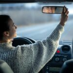 Happy young woman drives a car, inside view.